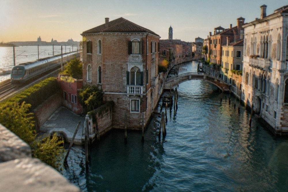 A regional train travelling along the coastal rail line towards the Venice lagoon