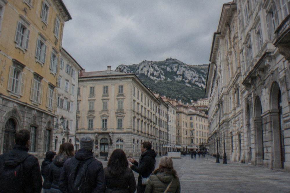 A local guide speaking to a small group on a square in central Trieste