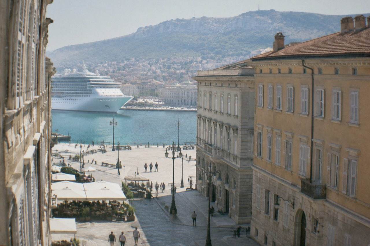A cruise ship tied up along the Trieste waterfront with the city's seafront squares beyond it