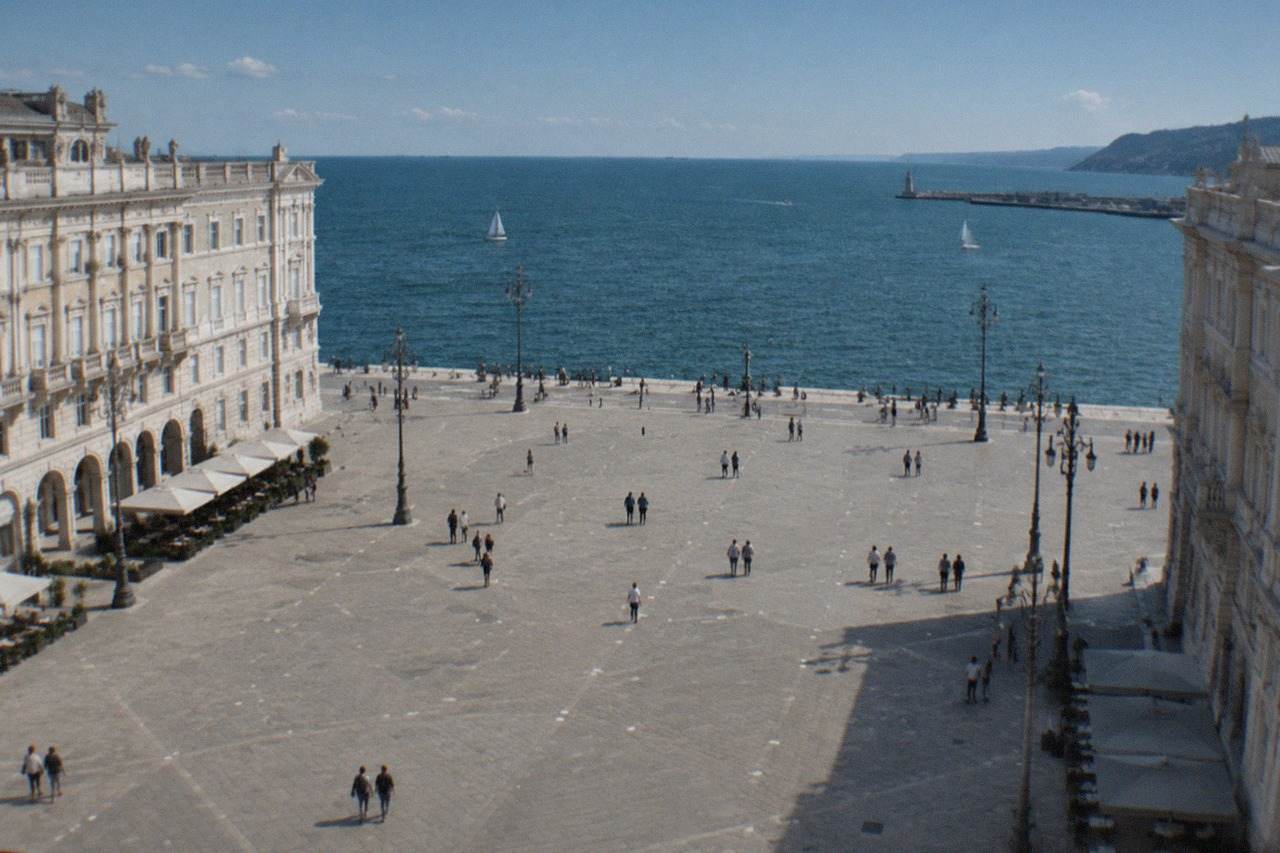 The seafront of Trieste, Italy, with Piazza Unità d'Italia's grand facades facing the water on a bright day.