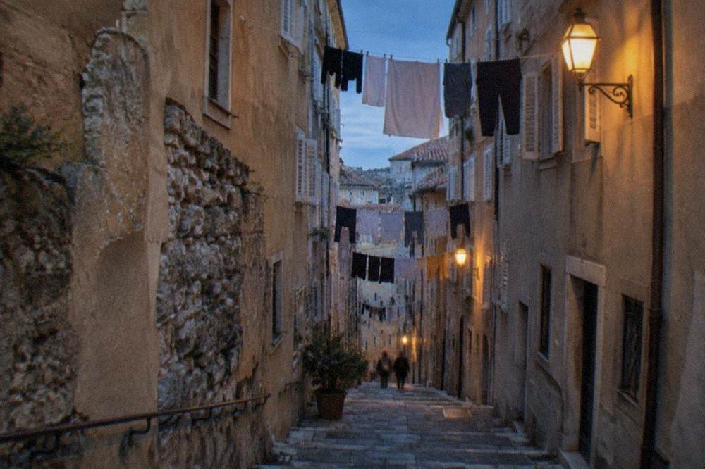 A quiet street in the Città Vecchia old town of Trieste with laundry strung above warm stone facades.