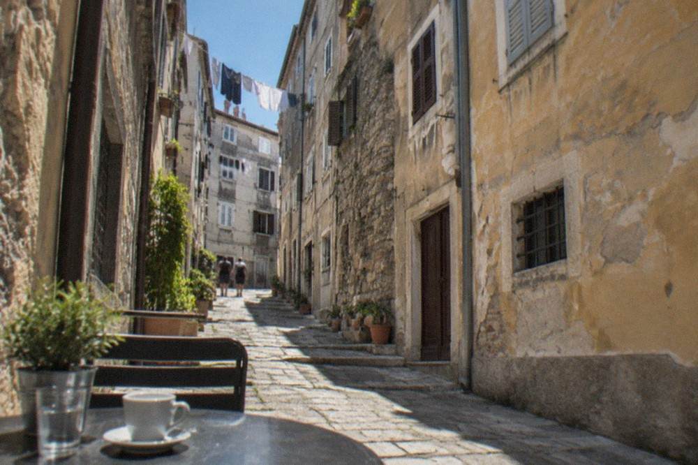 A narrow lane in Città Vecchia, Trieste's old town, with old facades above a cafe table