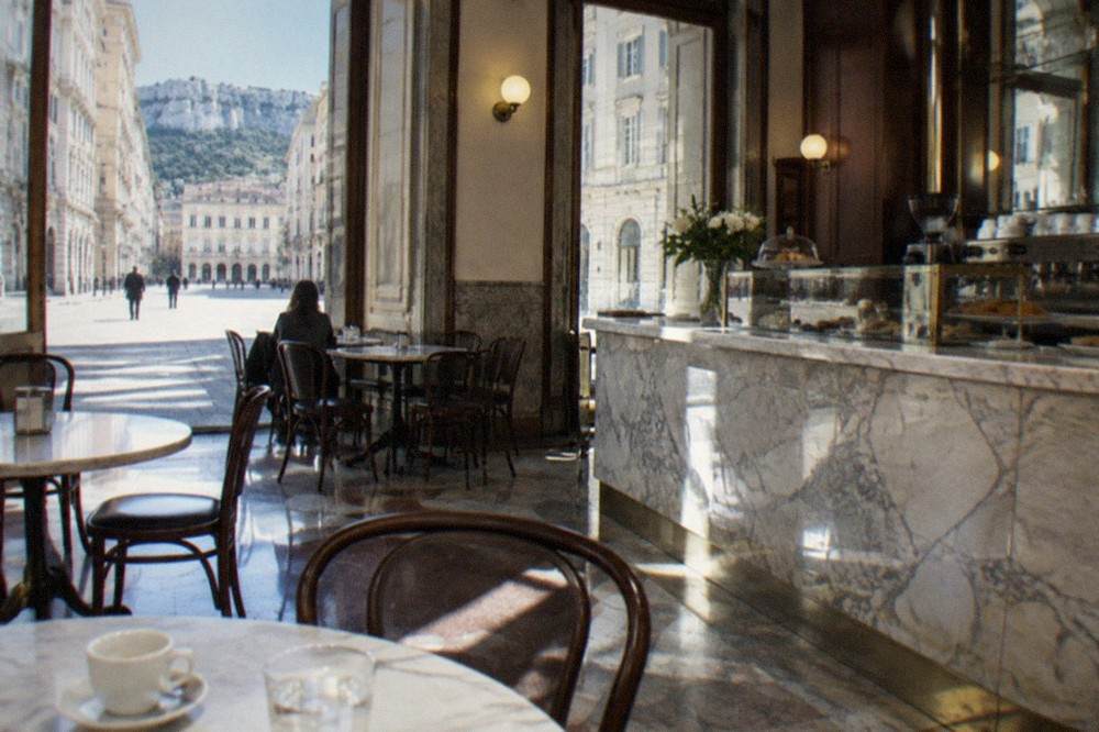 A historic Trieste caffe interior with marble tables and a marble counter