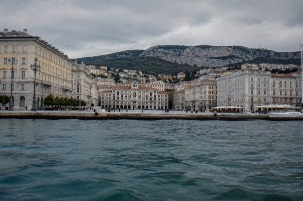 The seafront of Trieste seen from the water, with the grand square and hills behind the city