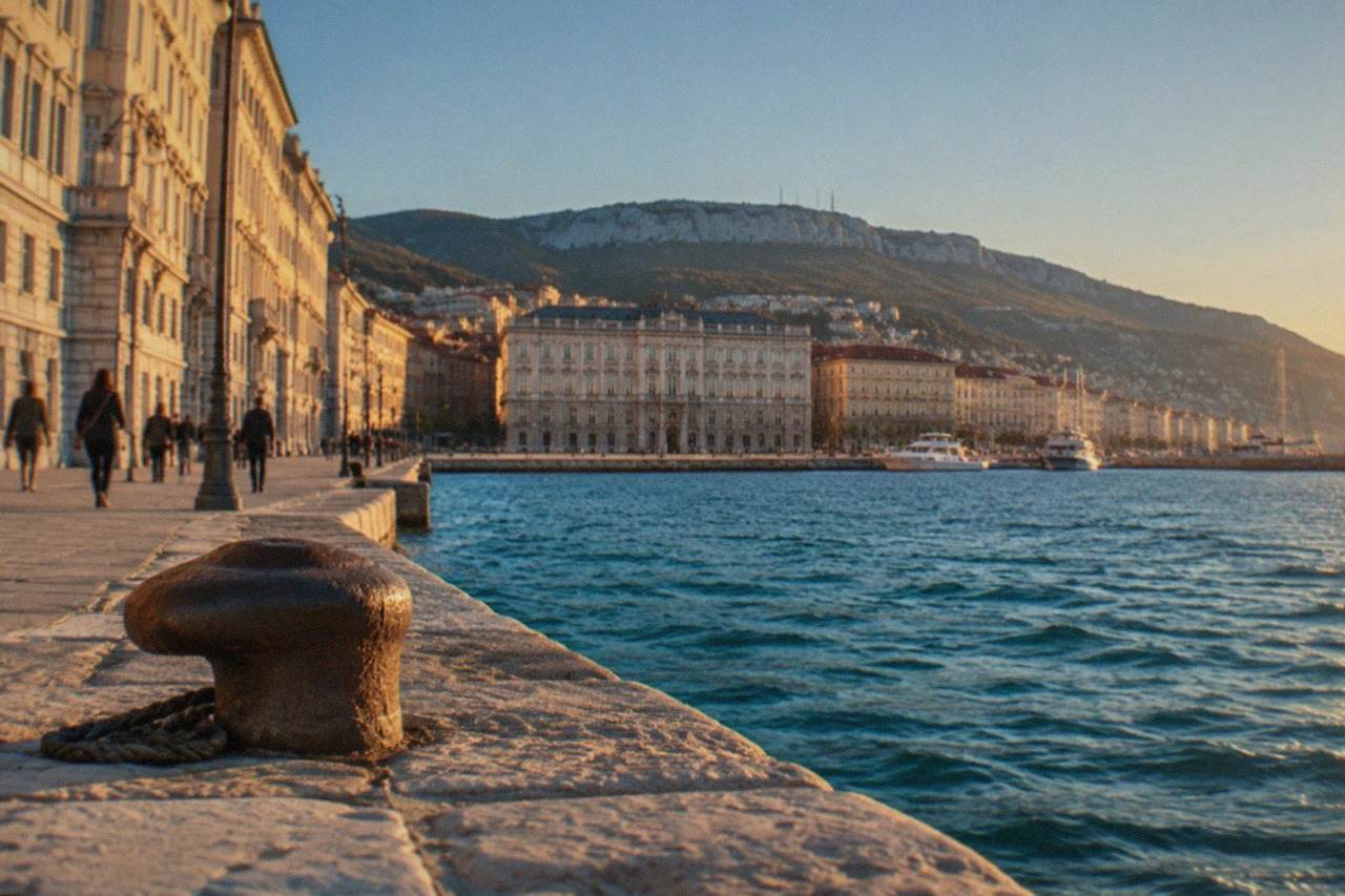 The waterfront of Trieste in Italy with the sea and distant hills under a clear sky