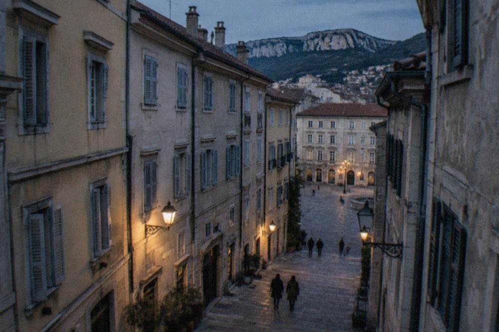 A narrow guesthouse street on the hillside old town of Trieste with stone buildings and shutters