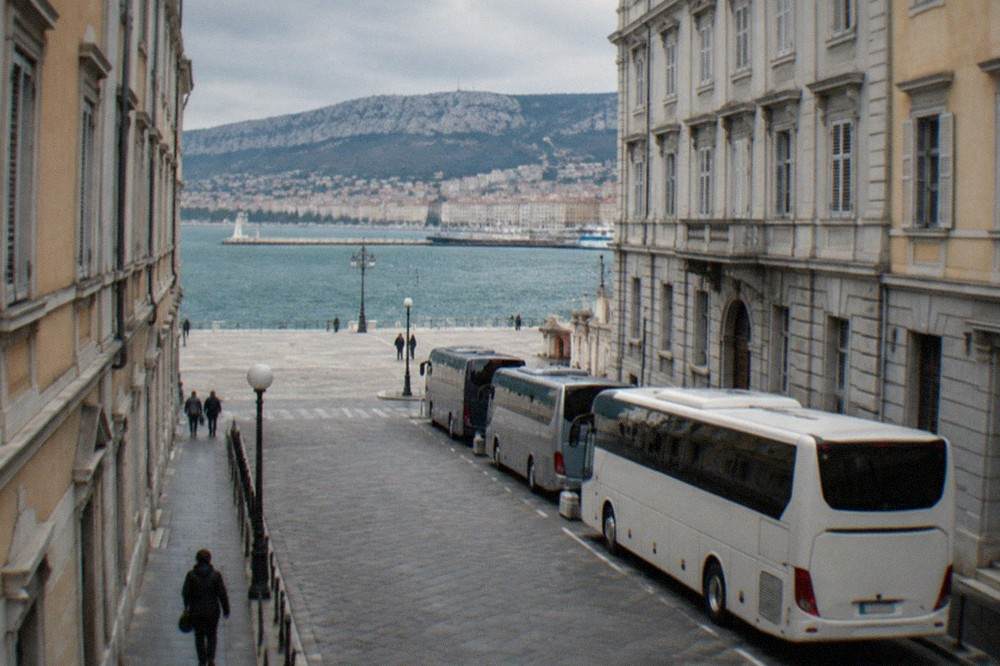 Coaches parked at a street-side coach stop near the seafront in Trieste