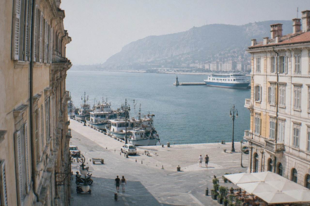 Fishing boats and a ferry tied up along the seafront of Trieste in Italy