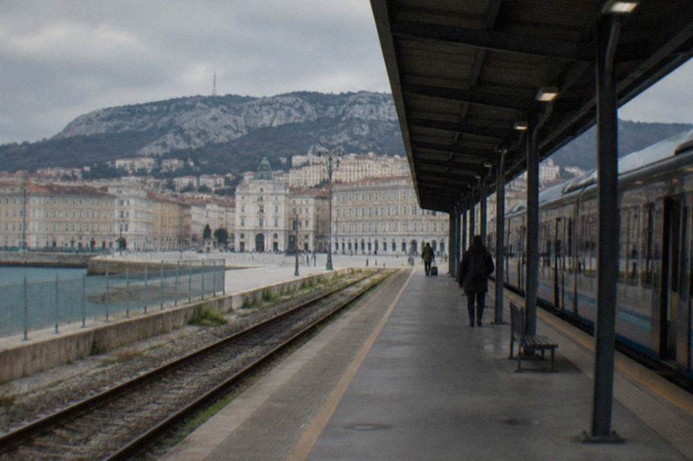 A train waiting at a small airport railway platform beside a covered walkway