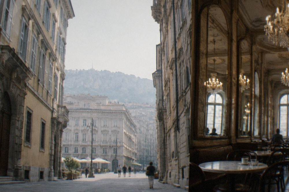 A historic Trieste coffee house interior with marble tables, mirrors and chandeliers