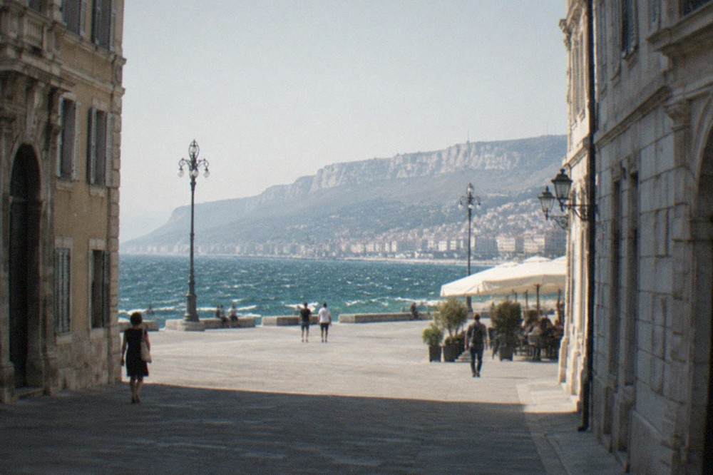 Whitecaps on the Gulf of Trieste seen from the seafront on a windy day, with the coastline curving toward distant hills