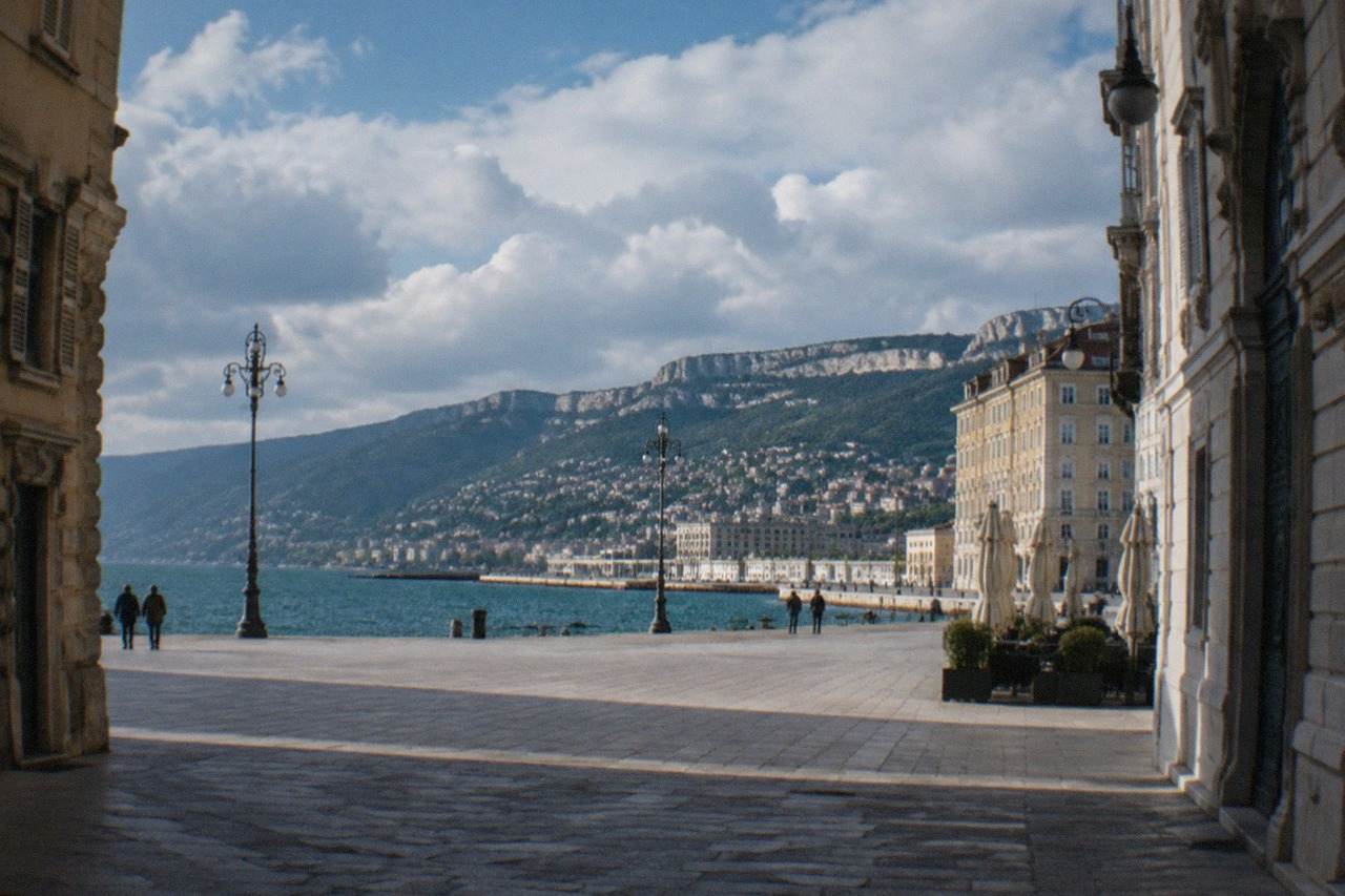 The seafront of Trieste, Italy, on a calm morning with the waterfront piazza and hills behind the Gulf of Trieste