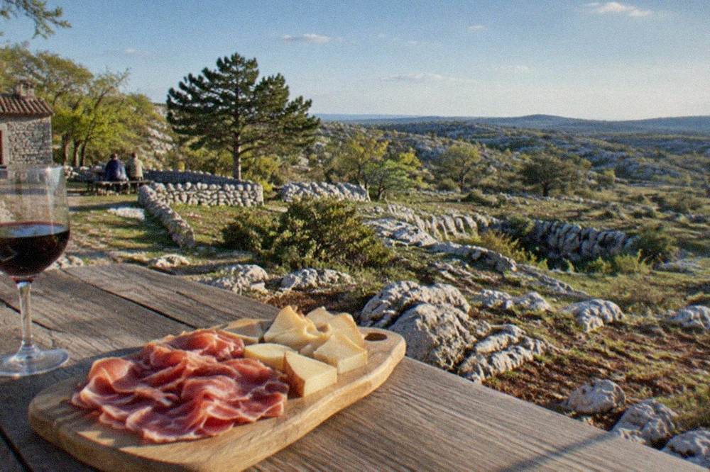 A wooden plate of cured ham and Terrano cheese served at an osmiza farmhouse on the Karst plateau