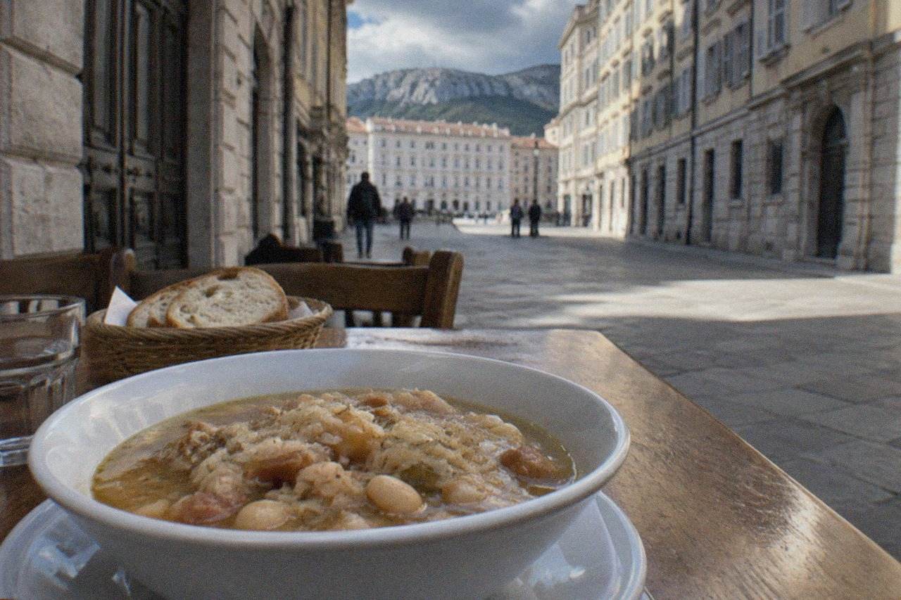 A bowl of thick soup with beans and sauerkraut on a wooden table in a small Trieste restaurant