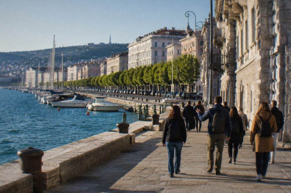 A small group with a guide walking through a narrow lane of Trieste's old town above the seafront