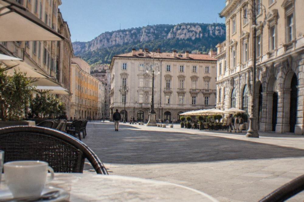 Sunlit square in central Trieste with café tables and Habsburg-era facades