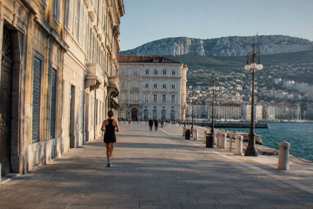 A walled Adriatic coastal town on a peninsula, seen from the water at golden hour.