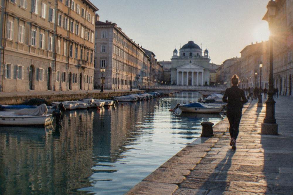 Boats moored in a city canal with a domed church at its far end
