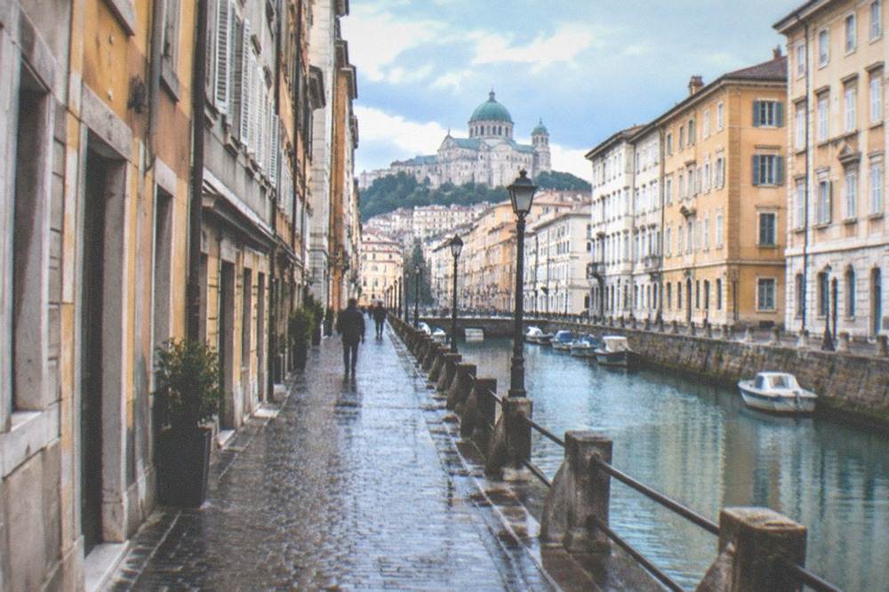 Narrow cobbled street with old buildings leading toward a hilltop cathedral