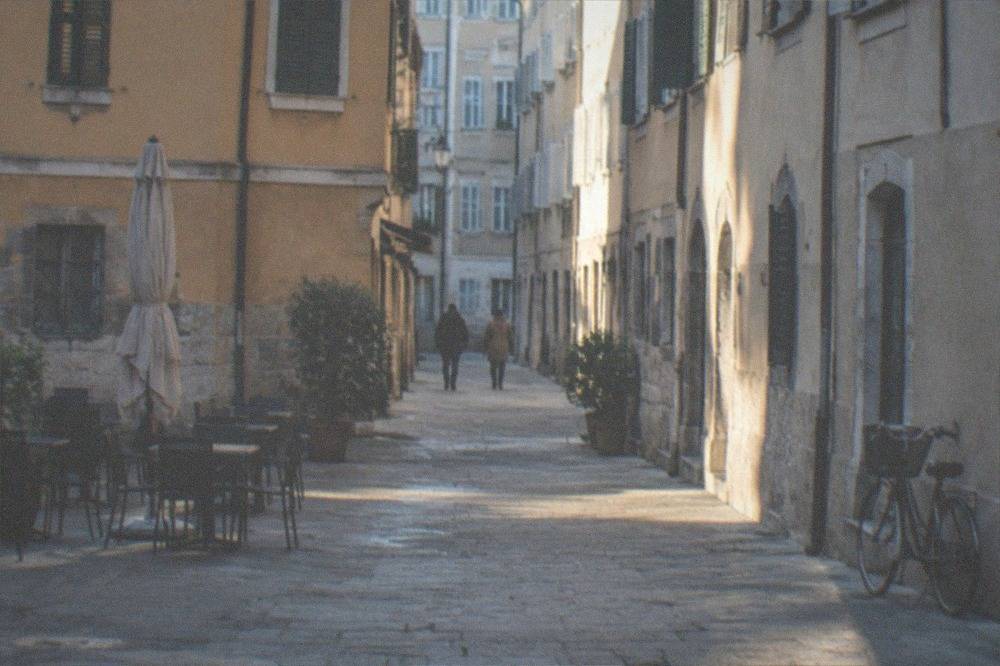 Pedestrian lane in Cavana Trieste with stone paving, shuttered windows and a bicycle leaning against a wall