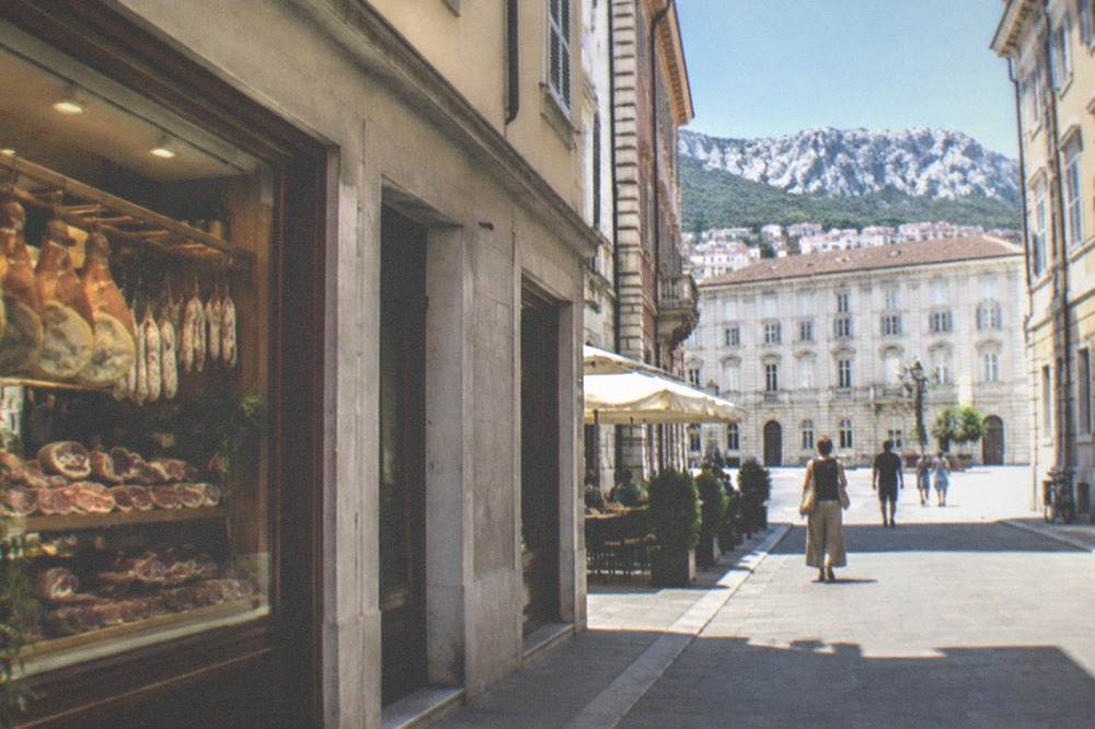 Small buffet restaurant in the old town of Trieste with a cured meat display in the window and a chalkboard menu
