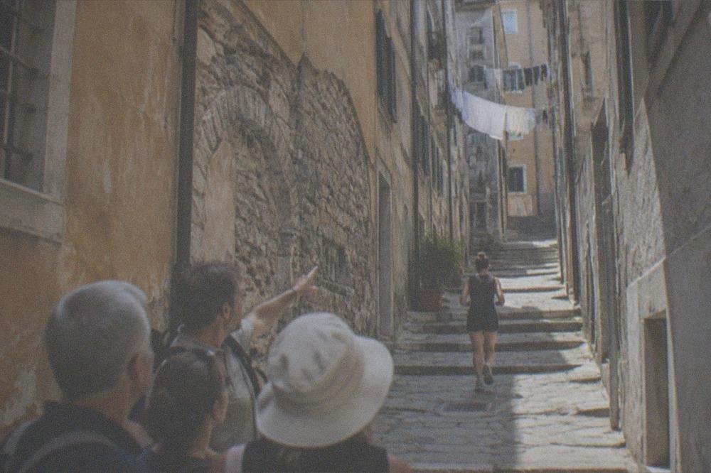 Guide pointing out details on a stone facade to a small group on an old town street