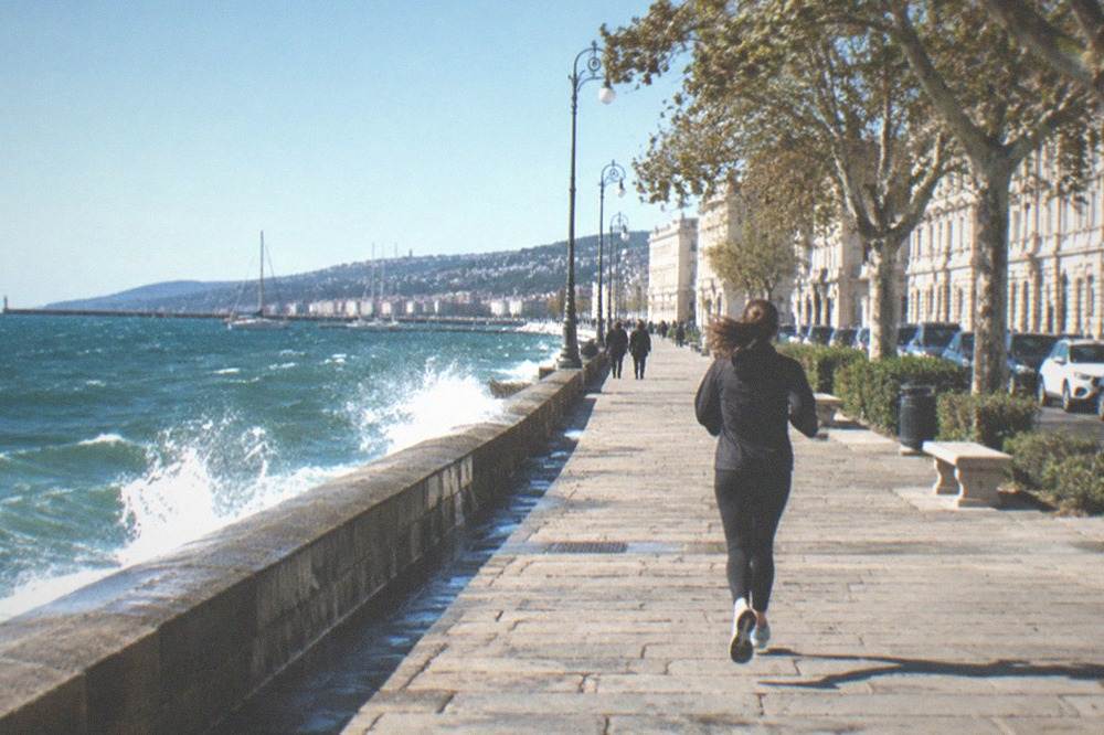 A wind-swept seafront promenade with waves breaking against a sea wall
