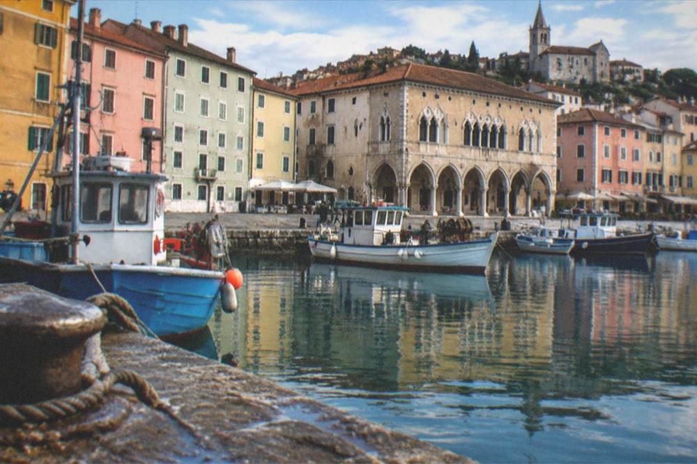 Fishing boats moored in Muggia harbour with the old town rising behind