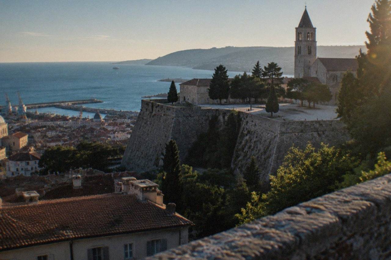 The hill of San Giusto in Trieste seen from the rooftops, with the castle ramparts and the cathedral bell tower above the old city