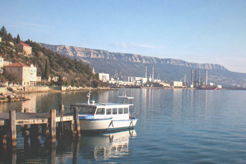 A small passenger boat moored at a wooden jetty on a calm bay morning