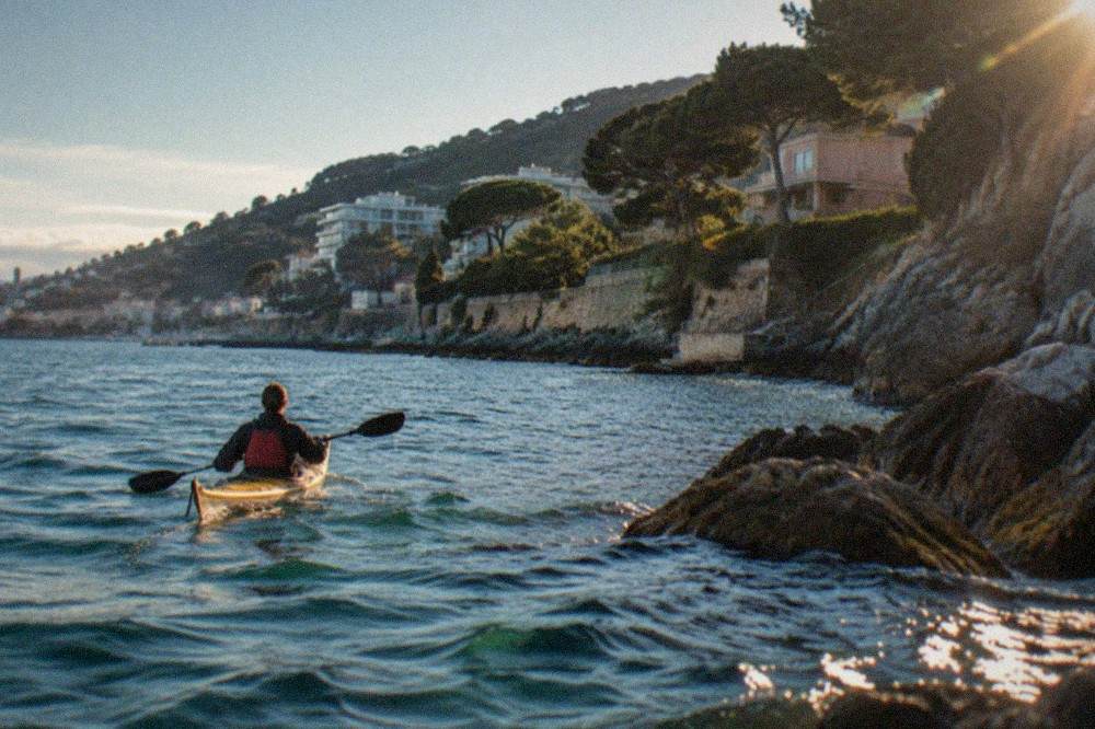 A kayaker paddling close to the rocky shoreline near Barcola with the Trieste coast behind