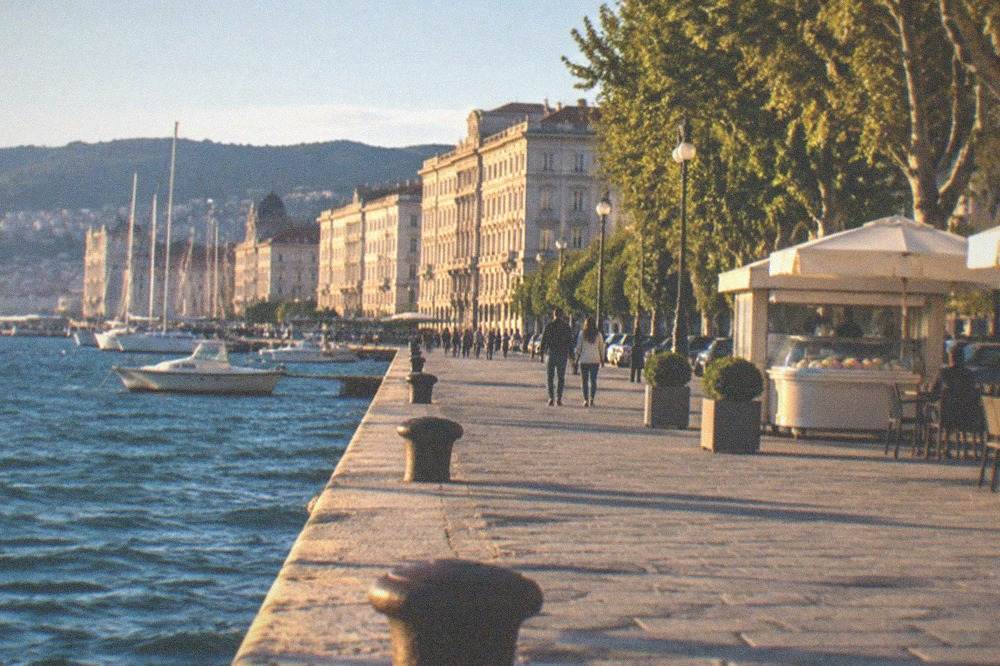 A gelato kiosk and outdoor tables on the seafront promenade in the evening light