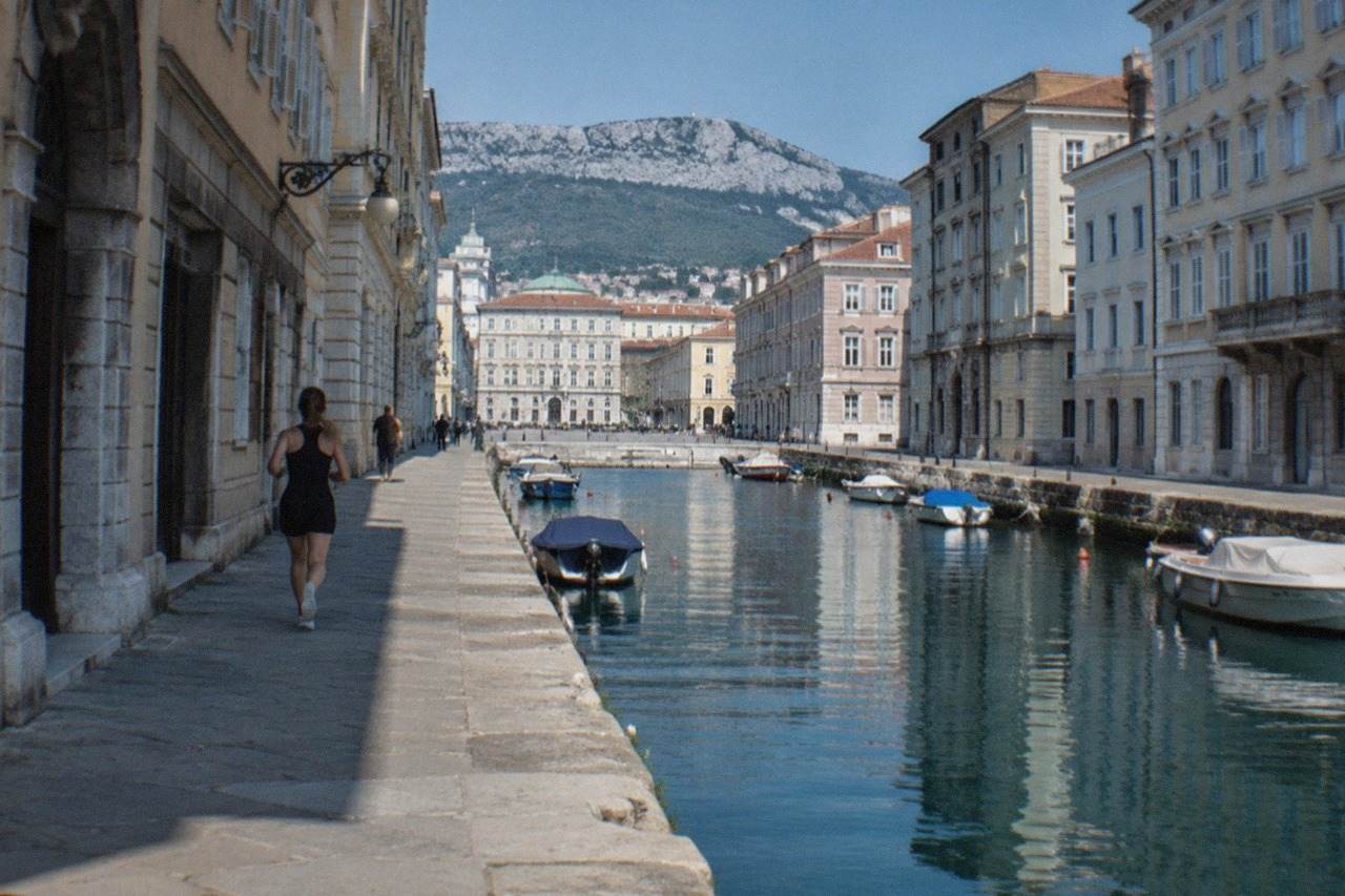 A narrow canal lined with pale buildings and small boats in Trieste, Italy