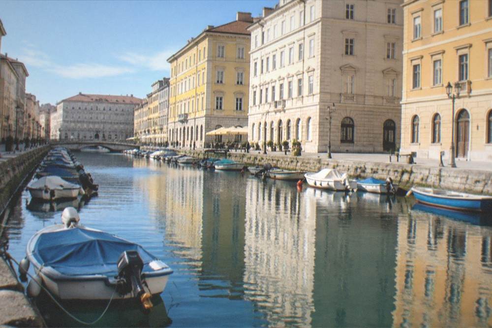 A canal in a European city at dusk with lit facades reflecting in still water