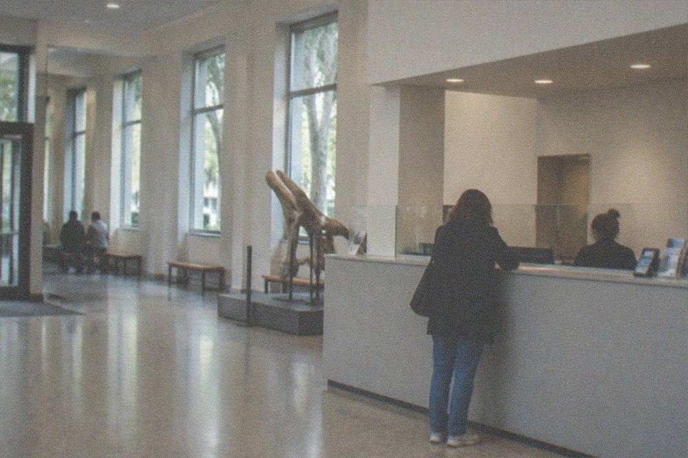 A ticket counter in a museum lobby with a visitor buying an admission ticket