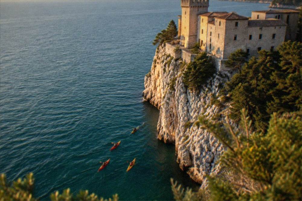 Kayaks paddling along the limestone cliffs below the Duino castles