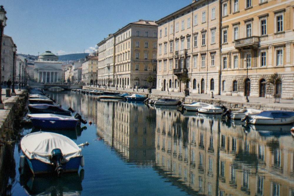 Neoclassical buildings along the Canal Grande in Trieste reflected in the still water of the canal