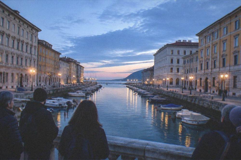 A guided walking group pausing on a bridge over the Canal Grande in Trieste