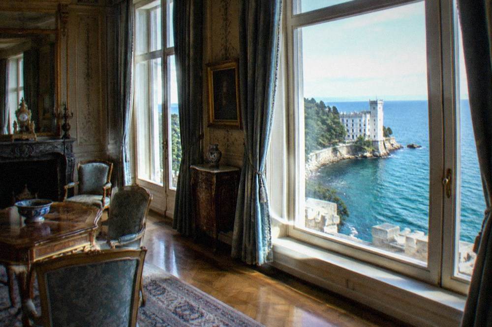 An ornate nineteenth-century state room with original furnishings and a view over the sea through tall windows
