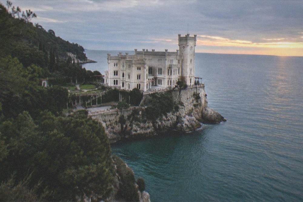 A white castle on a headland at golden hour with the sea calm on both sides