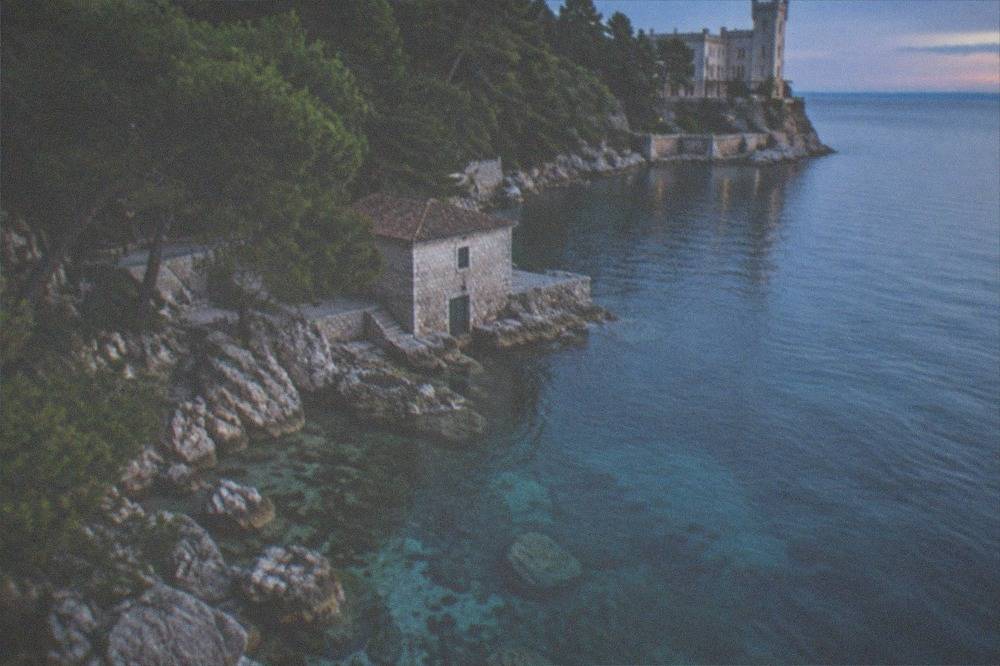 Clear shallow water over pale limestone rocks along the protected shoreline below the castle
