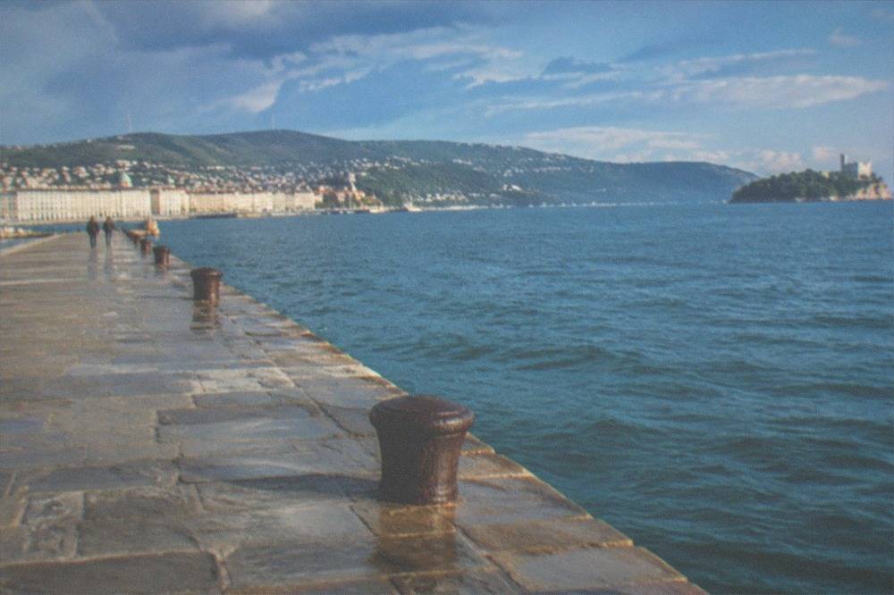A distant white castle on a headland seen across a wide blue gulf