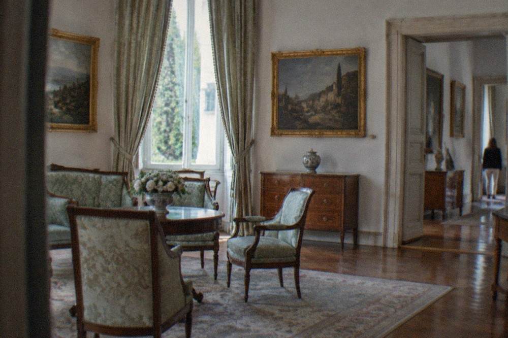 An elegant interior room of a Triestine villa museum with period furniture, drapery and framed paintings
