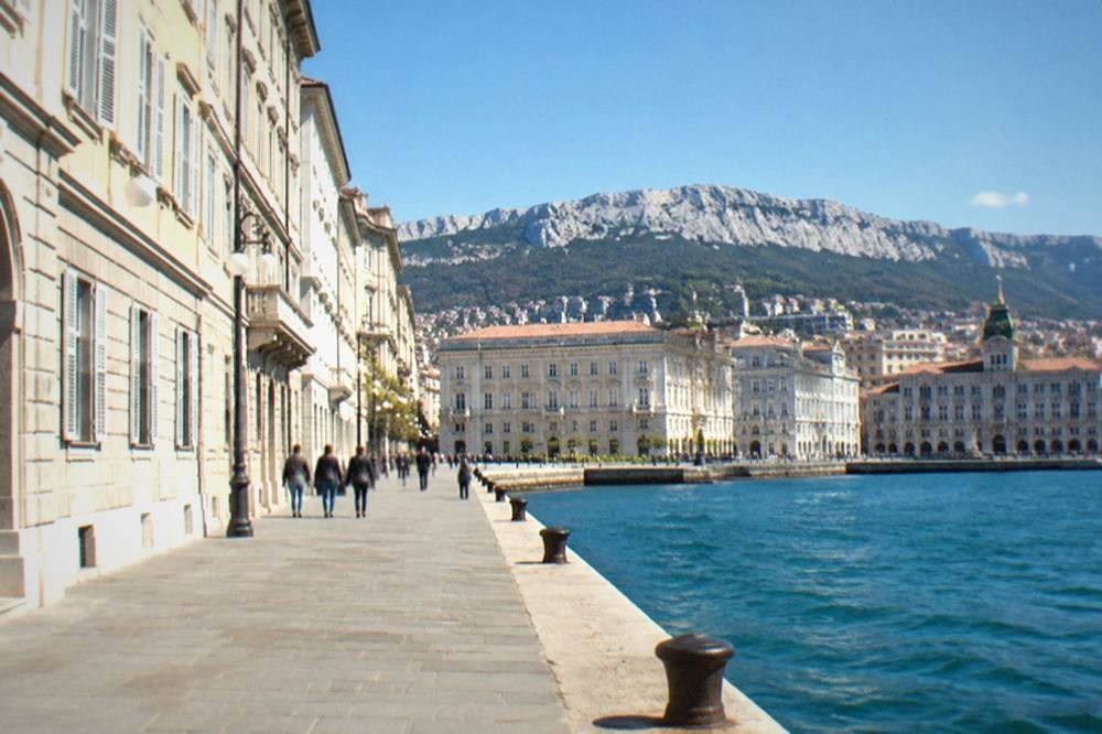 The Trieste waterfront road with the sea on one side and historic buildings on the other on a clear day