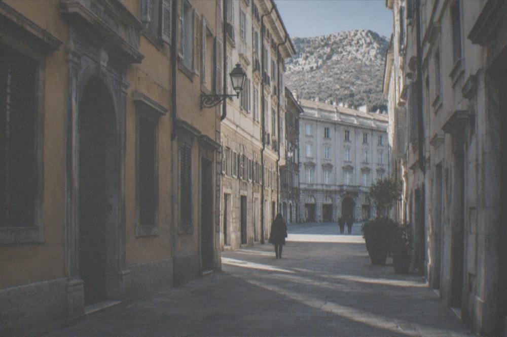 A narrow old-town lane in Trieste with stone buildings climbing a hillside