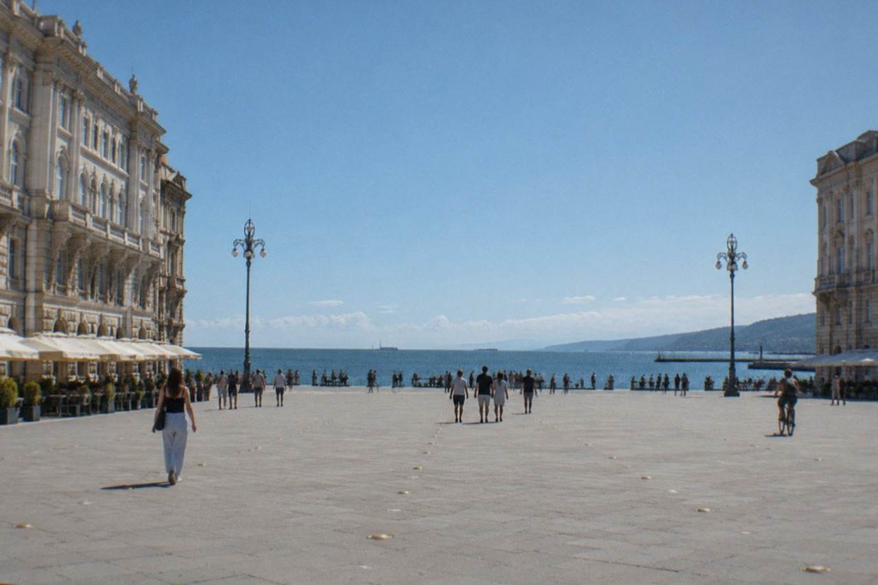 A wide Italian square beside the sea with grand ornate facades and an open view over the water