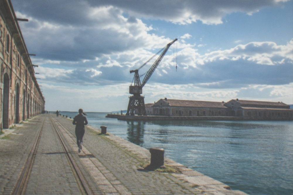 Wide view across the old port basin with warehouse roofs and the sea horizon