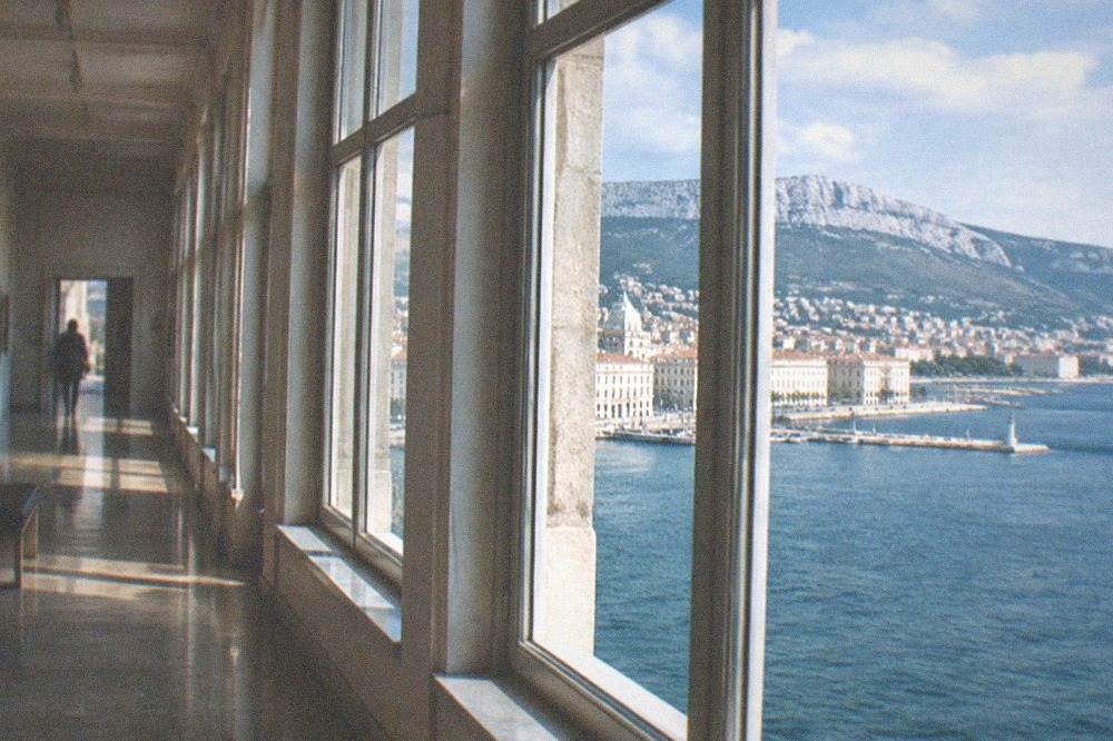 A quiet museum gallery corridor with tall windows overlooking the Adriatic sea