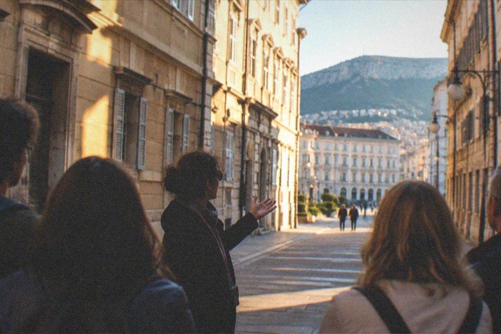 A small group with a guide standing on a Trieste street listening to an explanation