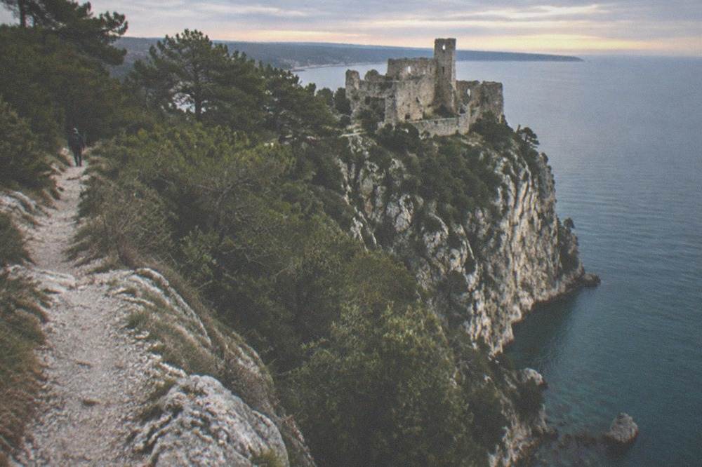 A stone ruin of an old castle on a cliff above the sea at golden hour